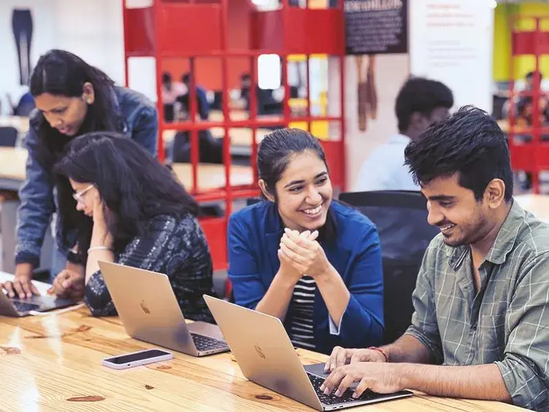 a group of people sitting at a table with laptops